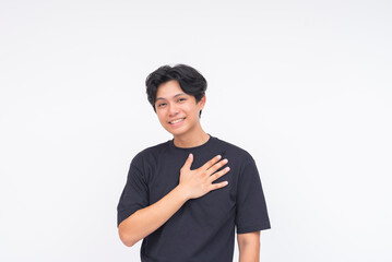 A warm young Asian man expressing sincerity with a heartfelt smile and hand on chest. Isolated on a...