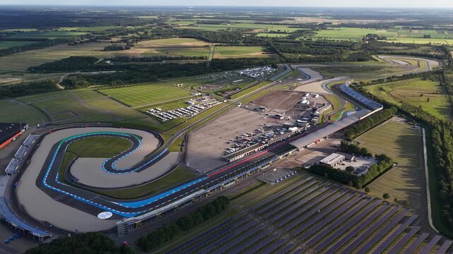 Aerial view of TT Circuit Assen glowing under a golden sunset, showcasing the track layout