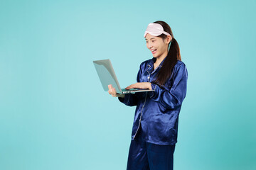 Happy asian woman with sleep mask working remotely with laptop, feeling relaxed and smiling in her...