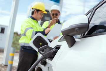 Workers operating an electric vehicle charging station in a sunny outdoor environment