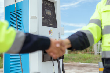 Technicians interacting at an electric vehicle charging station during daylight hours in a modern...