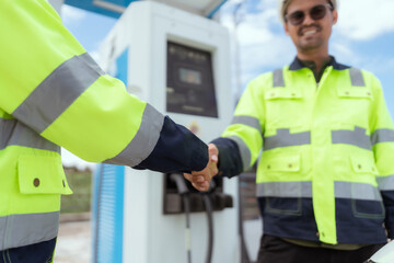 Technicians interacting at an electric vehicle charging station during daylight hours in a modern...