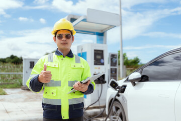 Engineer supervises electric vehicle charging station during the day in a modern urban setting