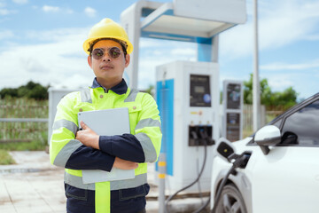 Engineer supervises electric vehicle charging station during the day in a modern urban setting