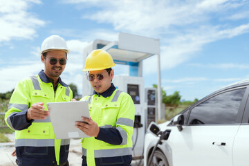 Electric vehicle charging experts discuss project details at a modern charging station in bright daylight