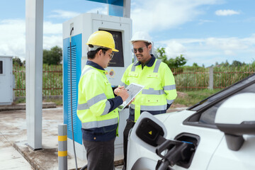 Engineers discuss electric vehicle charging station installation during sunny afternoon outdoors