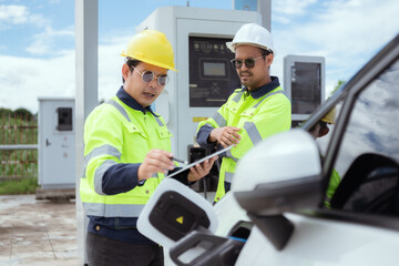 Workers operating an electric vehicle charging station in a sunny outdoor environment