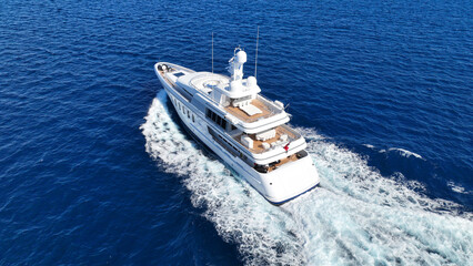 Aerial drone tracking photo of beautiful modern super yacht with wooden deck cruising in low speed...