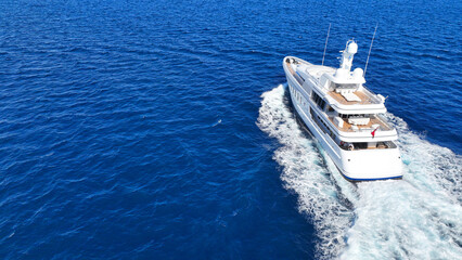 Aerial drone tracking photo of beautiful modern super yacht with wooden deck cruising in low speed...