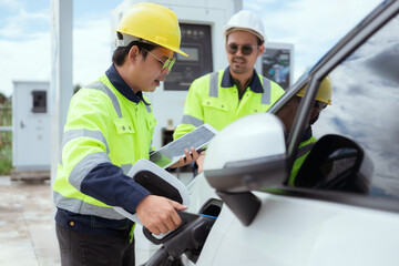 Workers operating an electric vehicle charging station in a sunny outdoor environment