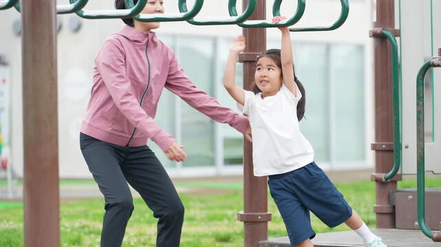 公園の雲梯で遊ぶ女の子