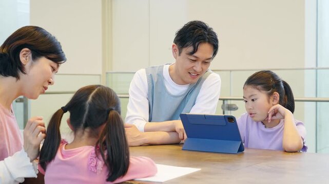タブレットを見る女の子と使い方を教える男性