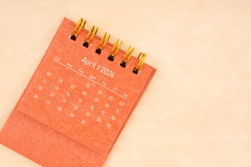 Mini red desk calendar for April 2026 year on old brown paper background, Flat lay.