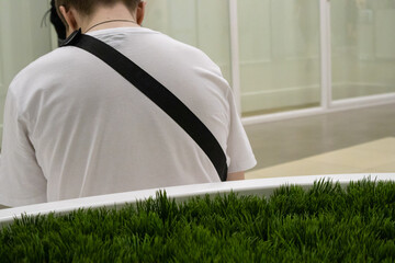 Rear view of a young man in a white T-shirt, leaning his head forward