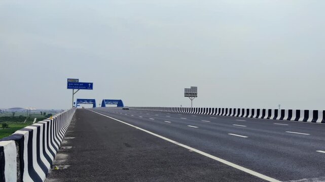 Footage of Delhi Vadodara Mumbai Expressway road and Toll Plaza shot against a beautiful cloudy sky
