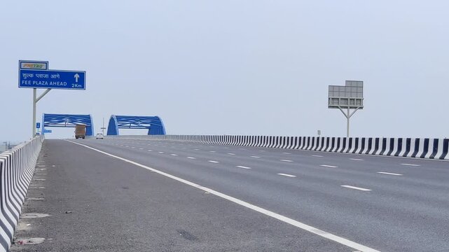 Footage of Delhi Vadodara Mumbai Expressway road and Toll Plaza shot against a beautiful cloudy sky
