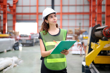 Engineer or worker writing on clipboard beside machine in the factory