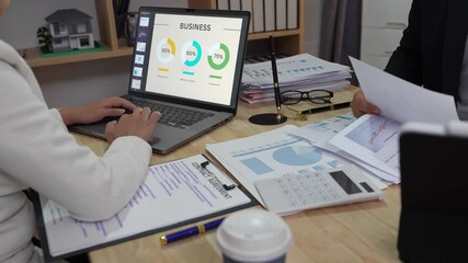 Asian business couple having financial meeting at night planning home finance in living room happily using laptop and tablet working at conference table - Powered by Adobe