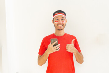 Young Indonesian man thumbs up to mobile phone with headband in isolated white