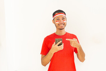 Young Indonesian man pointing to mobile phone with headband in isolated white