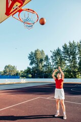 happy moment on court, Asian teen girl in red shirt enjoying basketball training outdoors, motion blur
