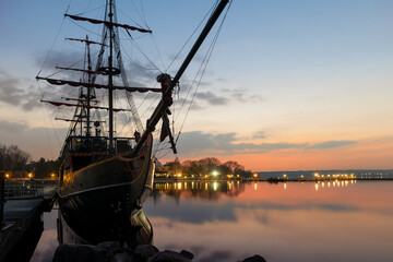 On a spring evening at sunset, an ancient frigate with scarlet sails stands frozen in time at the pier