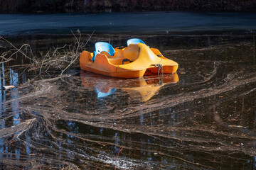 An orange pedal catamaran floats in dirty water