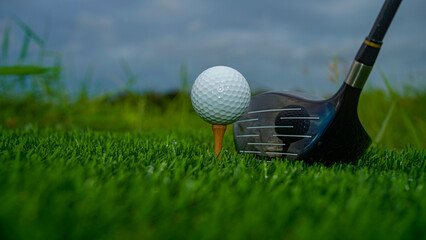 Golf clubs and balls on a green lawn in a beautiful golf course with morning sunshine.