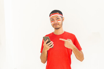 Young Indonesian man pointing to mobile phone with headband in isolated white