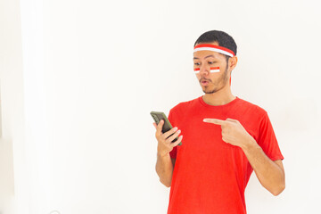 Young Indonesian man pointing to mobile phone with headband in isolated white