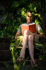 Man Reading a Book in the Garden Overgrown by Ivy and Vines