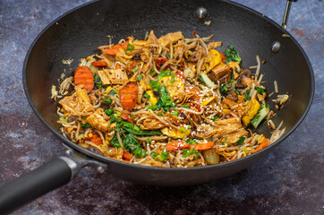 Vegan stir fried yuba, carrot, mung bean sprouts. Cast iron wok on a stylish surface