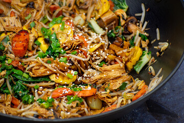 Vegan stir fried yuba, carrot, mung bean sprouts. Cast iron wok on a stylish surface