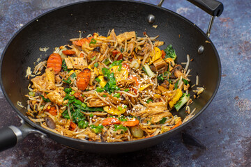 Vegan stir fried yuba, carrot, mung bean sprouts. Cast iron wok on a stylish surface