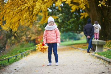Cheerful little girl enjoying her walk in autumn park in Paris, France.