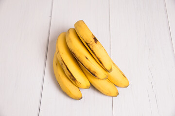 Branch of bananas with spoiled skin on a gray light table