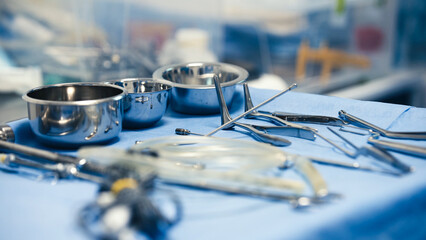 Surgical instruments arranged on a blue surgical drape, showcasing various tools including bowls,...