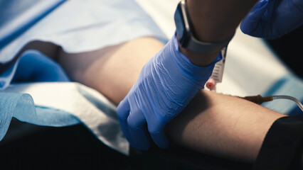 Medical professional in blue gloves prepares to draw blood from a patients arm in a clinical...
