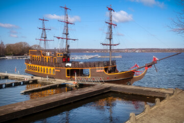 On a spring day, an ancient frigate with scarlet sails stands frozen in time at the pier