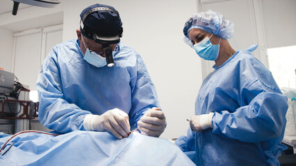 Medical professionals performing septoplasty and rhinoplasty surgery in a sterile operating room,...