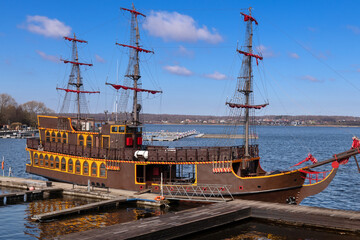 On a spring day, an ancient frigate with scarlet sails stands frozen in time at the pier