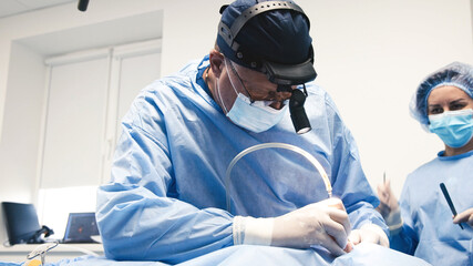 Medical professional in blue surgical attire is performing a procedure with precision, focused on...