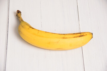 One banana with a damaged peel on a gray light table. Rescue the lonely banana