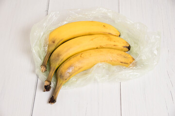 Spoiled bananas in a plastic bag on light background