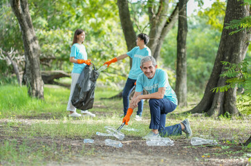 portrait asian senior man picking up used plastic bottle on ground with background diverse team of...