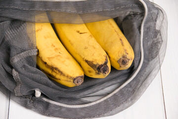 Spoiled bananas in an eco-bag on light background