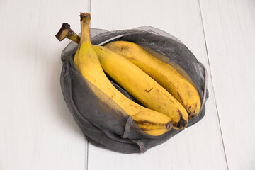 Spoiled bananas in an eco-bag on light background