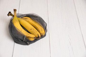 Spoiled bananas in an eco-bag on light background