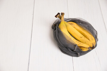 Spoiled bananas in an eco-bag on light background