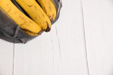 Spoiled bananas in an eco-bag on light background
